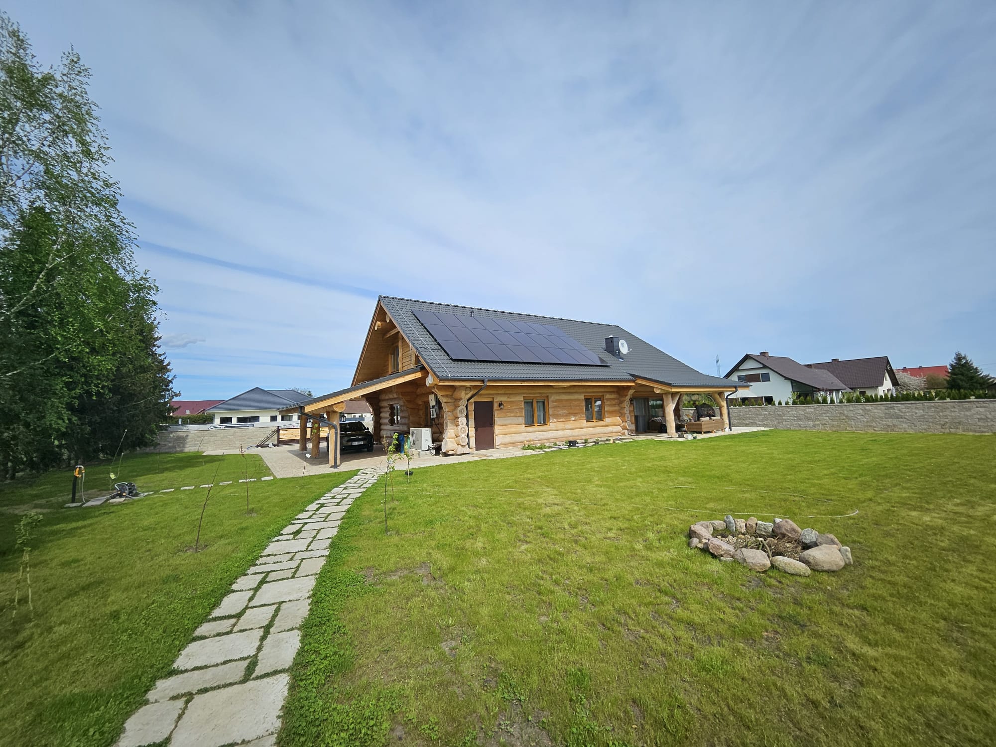 Instalacja fotowoltaiczna full black na dachu domu z bali — panele idealnie wpasowane w ciemną dachówkę