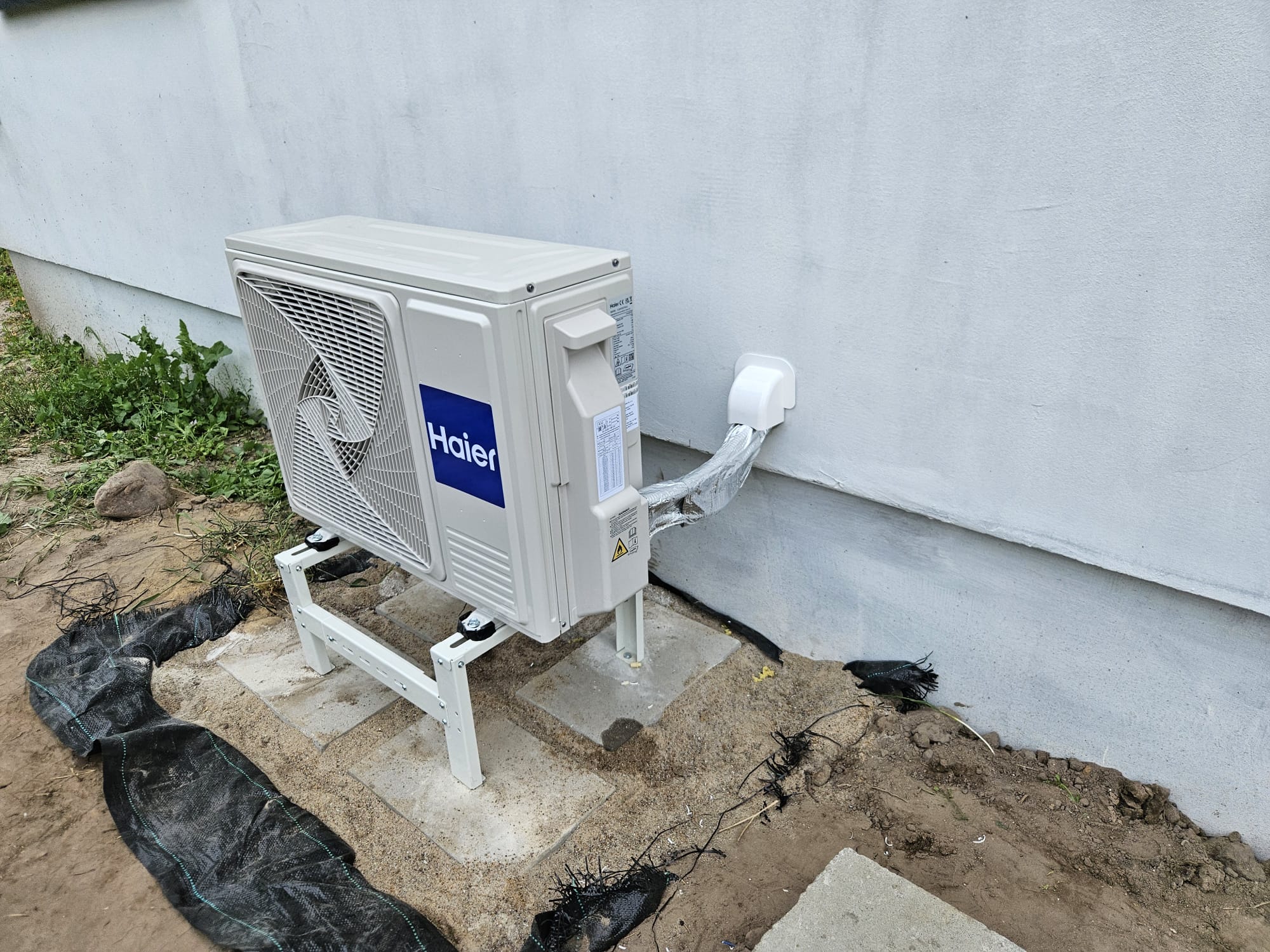 Klimatyzacja Haier — jednostka zewnętrzna na stojaku przy elewacji domu — PER-TECH